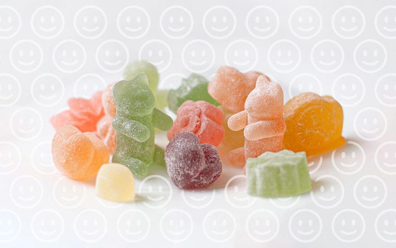 green, purple and orange gummy bears on a white surface